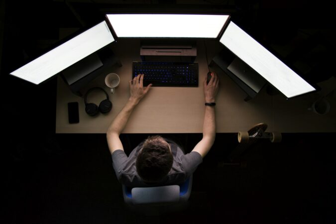 Administrator facing three computer monitors, representing managing WordPress users with AI